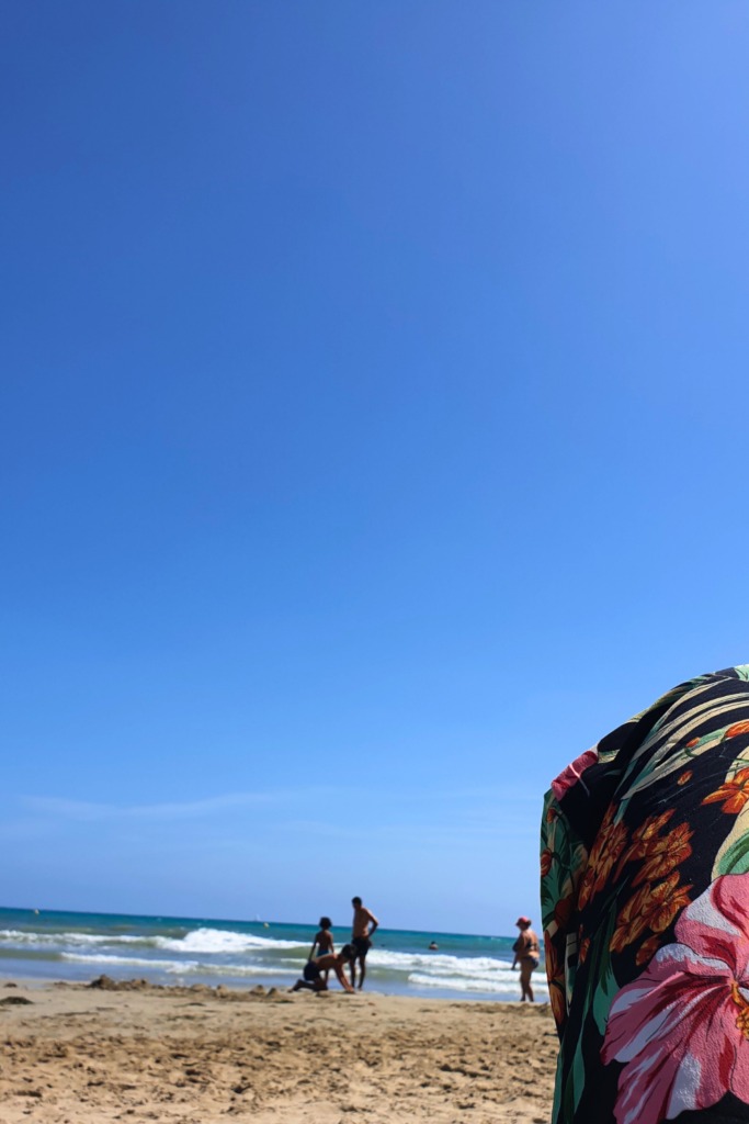 Blue sky at Playa del Postiguet's beach, Alicante, Spain. People standing in the sea.