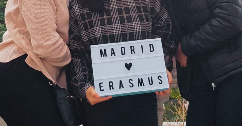 Friends holding a "Madrid Erasmus" sign