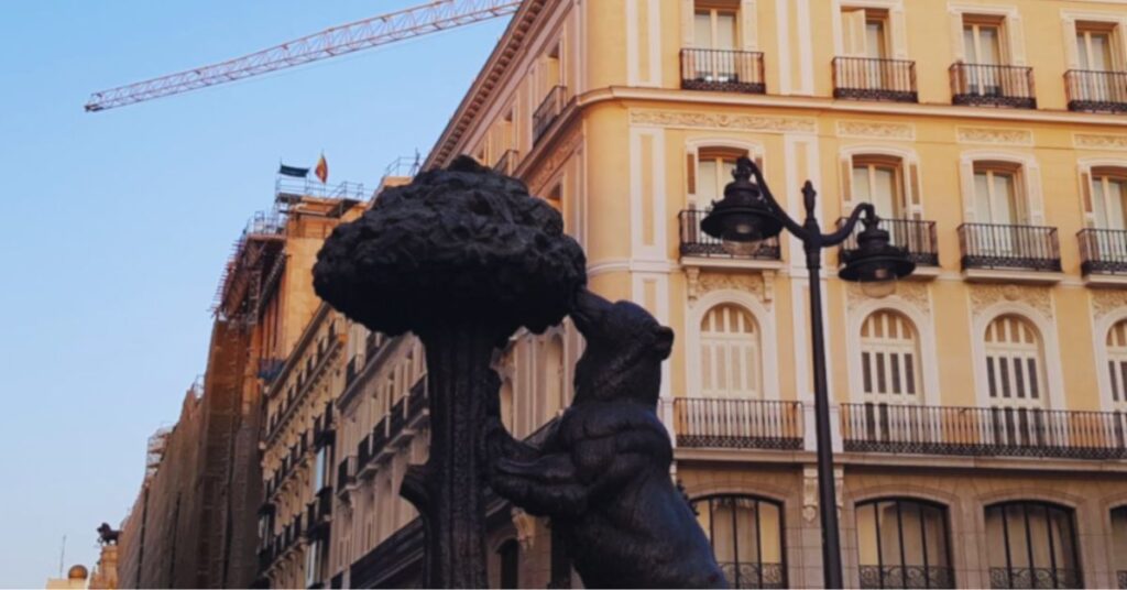 Statue of the bear and strawberry tree at Puerta del Sol in Madrid, Spain, with historic buildings in the background.